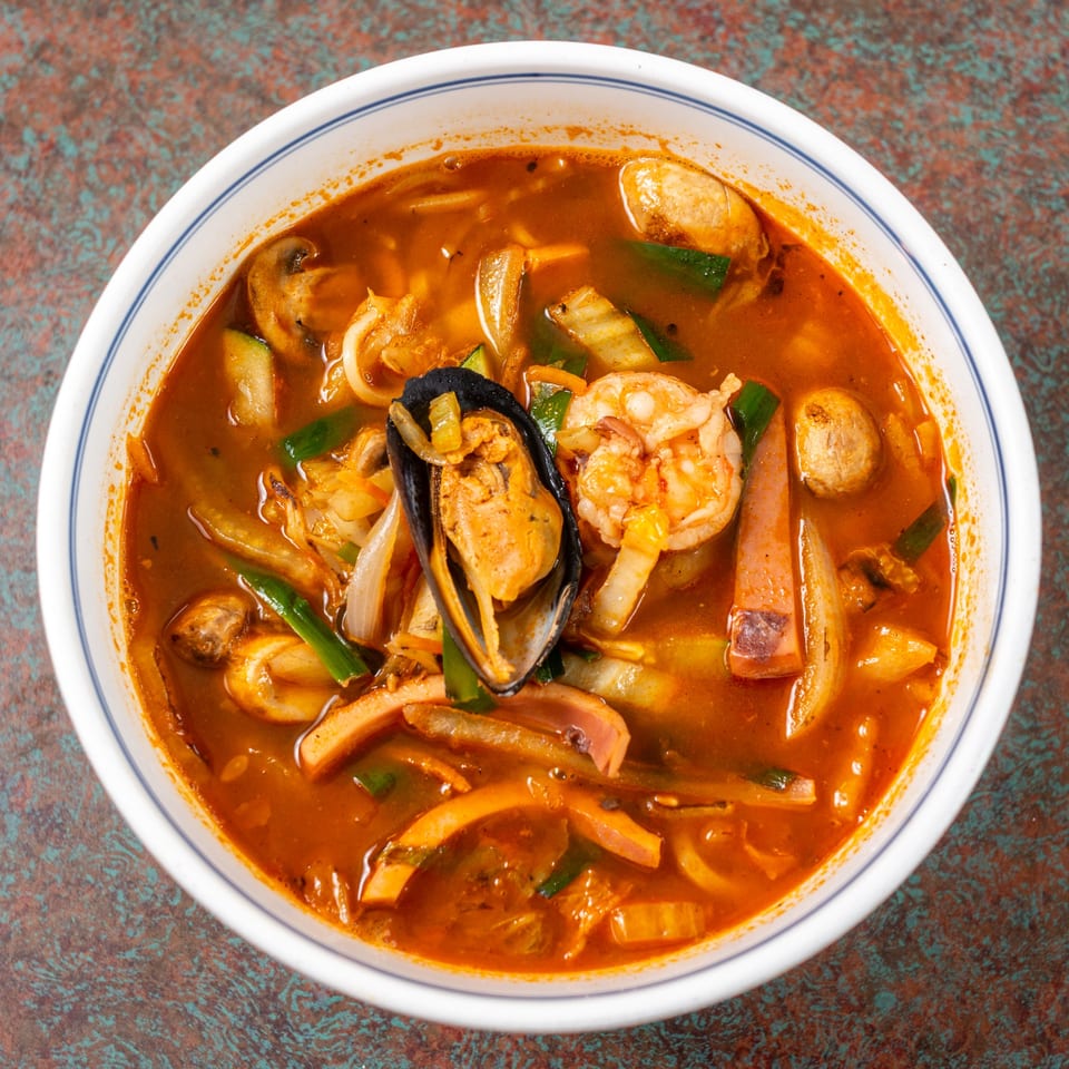 A bowl of Ming's spicy Chinese seafood noodle soup with shrimp, mussels, and vegetables.