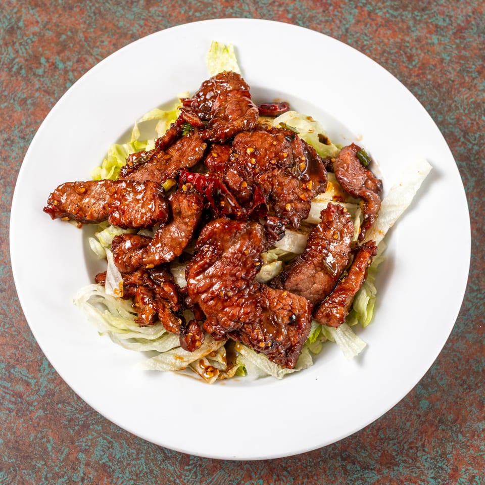 Ming's Restaurant's spicy beef with chili flakes and green onions on a bed of lettuce.