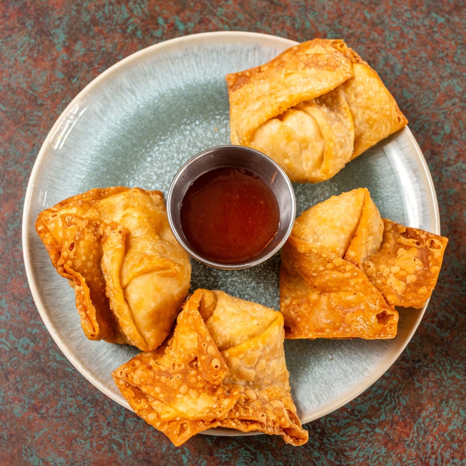 Ming's Restaurant's crispy fried wontons arranged around a small cup of sweet and sour dipping sauce.